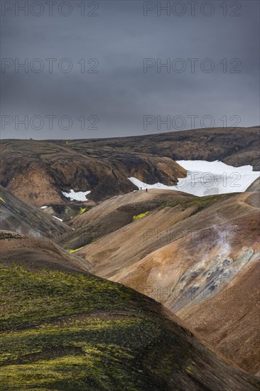 Hikers on colourful rhyolite mountains with remnants of snow