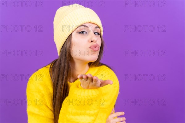Photo portrait of a young woman blowing a kiss isolated on a purple background