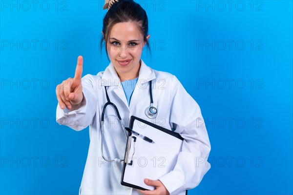 Portrait of smiling female doctor in medical gown standing isolated on blue