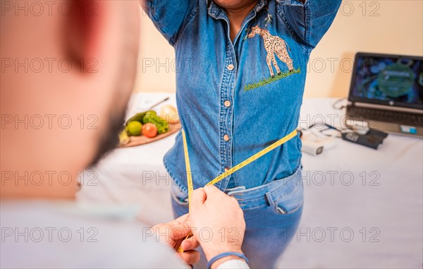 Close-up of nutritionist measuring waist to patient. View of a male nutritionist measuring female patient waist. Concept of weight loss and professional nutritionist