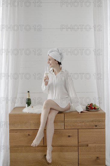 Portrait of an attractive woman with a towel on her head drinking champagne