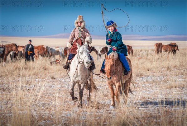 Happy children riding horses in winter. Dornod Province. Mongolia
