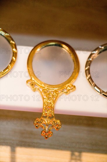 Little decorative gold color hand mirror on a shelf