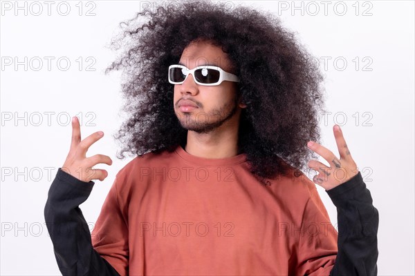 Portrait wearing sunglasses and doing the rapper symbol. Young man with afro hair on white background