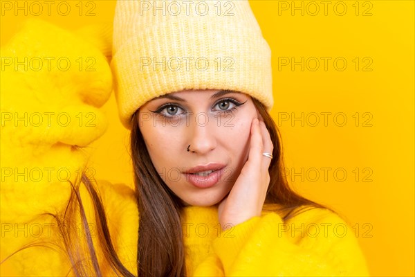 Close up portrait of young caucasian woman in woolen sweater isolated on yellow background