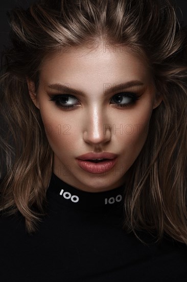 Portrait of a beautiful woman in a black dress with creative makeup in a fashion style. Beauty face. The photo was taken in a studio on a black background