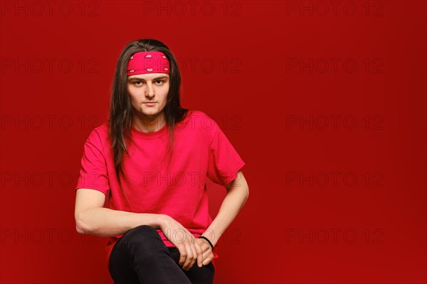 Studio portrait of confident young man with red head band and shirt