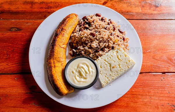 Gallopinto plate with cheese and maduro on wooden table. Nicaraguan food concept