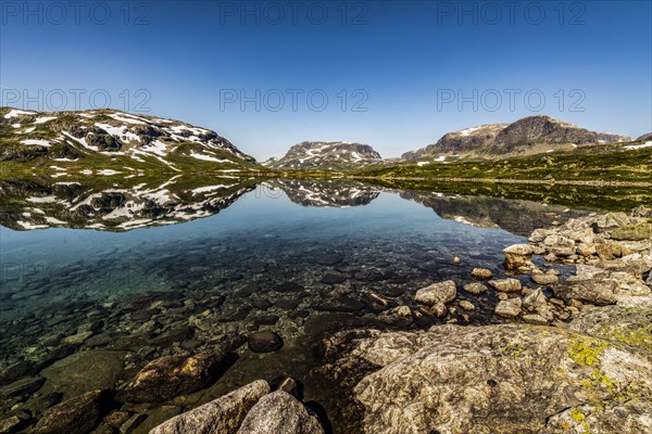 Reflection of partly snow-covered mountains in Lake Stavatn in Haukelifjell