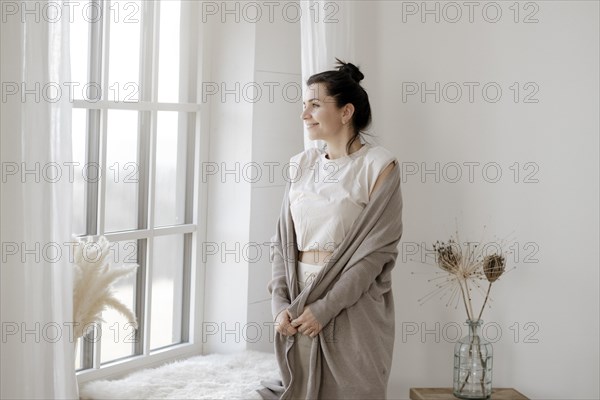 Dark-haired woman stands relaxed at the window