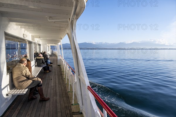 Passengers sitting on the outside deck of a passenger ship