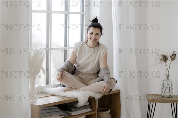 Dark-haired woman sits relaxed at the window