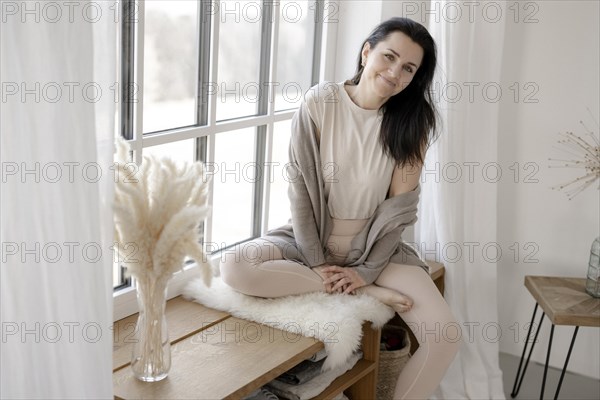 Dark-haired woman sits relaxed at the window