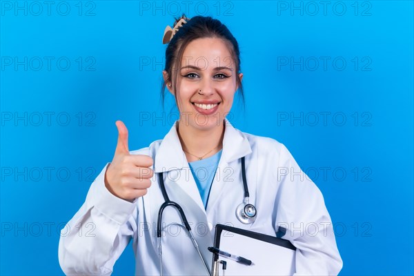 Portrait of smiling female doctor in medical gown standing isolated on blue