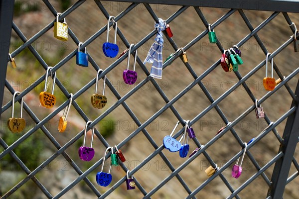 Many colorful metal love padlocks on fence