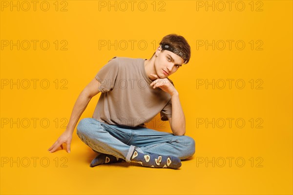 A young adult man dressed in rolled jeans and olive t shirt