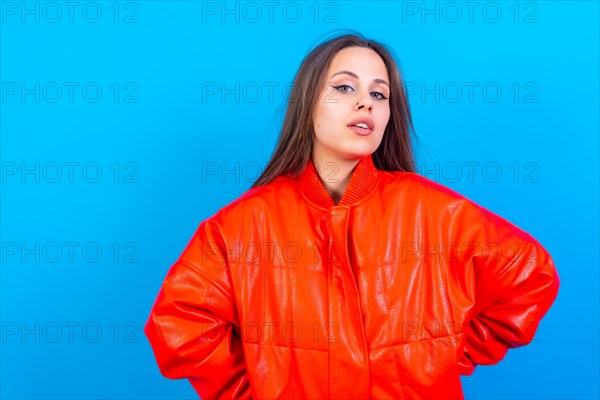 Close up portrait of young caucasian woman in red windbreaker isolated on blue background
