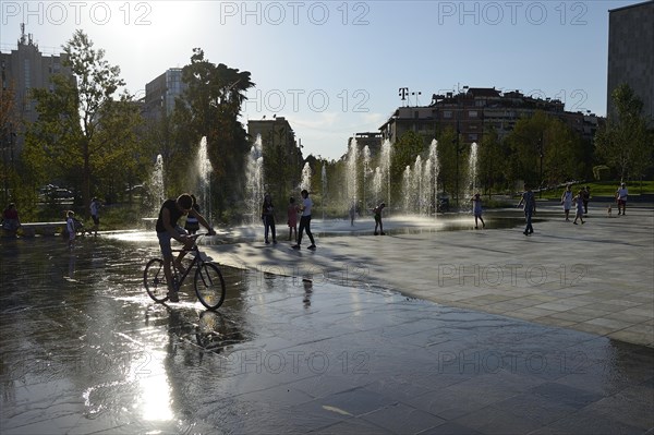 Fountain and cyclists in the backlight