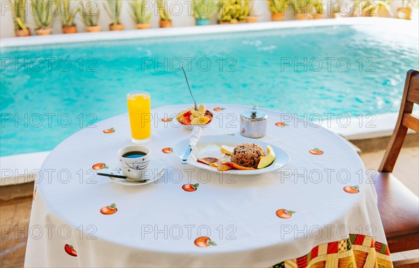 Traditional breakfast served at the table near a swimming pool. Breakfast served on the table with a swimming pool in the background. fruit salad