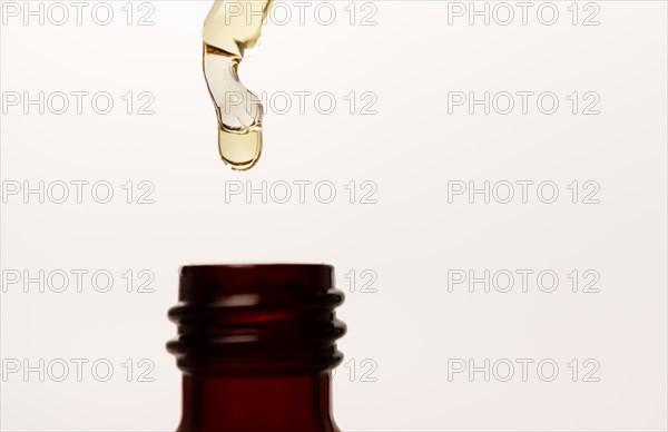 Close-up of a serum pipette with a falling drop on a white background