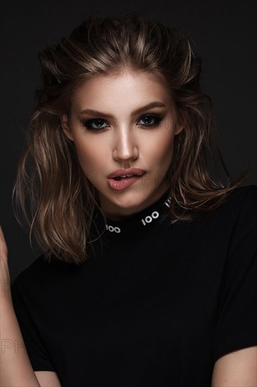 Portrait of a beautiful woman in a black dress with creative makeup in a fashion style. Beauty face. The photo was taken in a studio on a black background