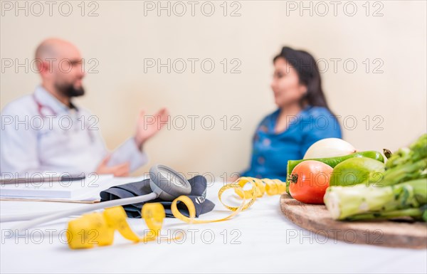 Nutritionist man with woman patient in office. Nutritionist talking to female patient with focus on the fruits in the foreground. Concept of nutritionist advising female client