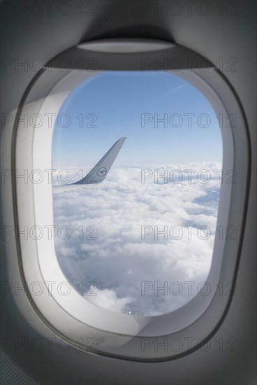 View from a window onto the wing of a Lufthansa aircraft over a sea of clouds