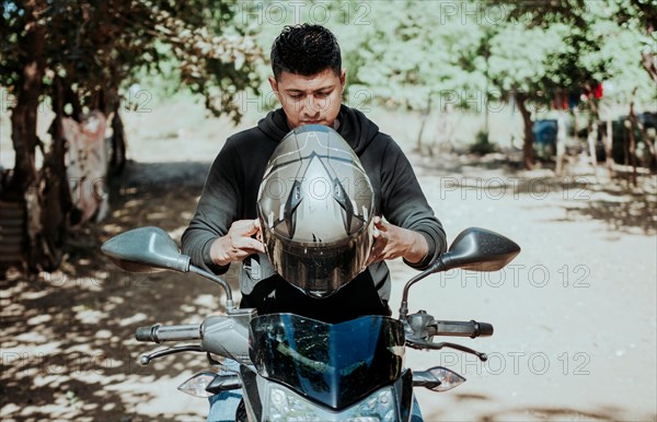 Man on motorcycle putting on helmet. Motorcyclist putting on safety helmet