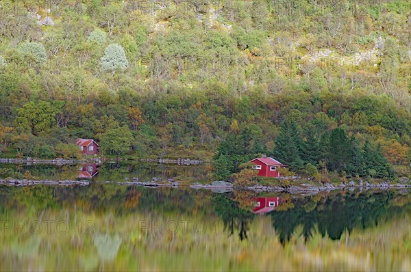 Small wooden houses reflected in the smooth water of a lake