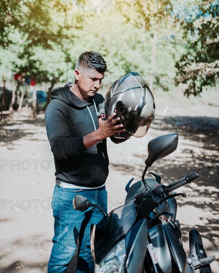 Man on motorcycle putting on helmet. Person on motorcycle putting on safety helmet. Biker motorcycle safety concept. Young motorcyclist man putting on safety helmet