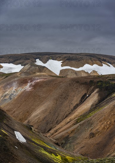 Hikers on colourful rhyolite mountains with remnants of snow