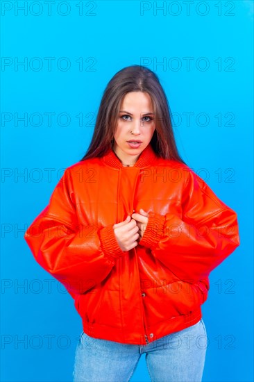 Close up portrait of young caucasian woman in red windbreaker isolated on blue studio background