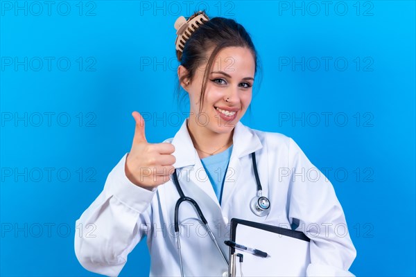 Portrait of smiling female doctor in medical gown standing isolated on blue