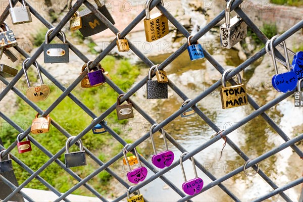 Many colorful metal love padlocks on fence