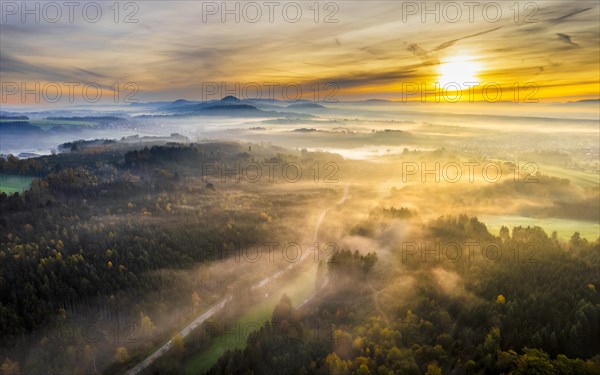 Drone view of sunrise over forest and rural landscape in autumn