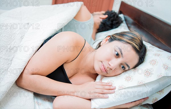 Young couple arguing and sleeping apart. Concept of couple problems in bed. Unhappy couple in bed sleeping apart
