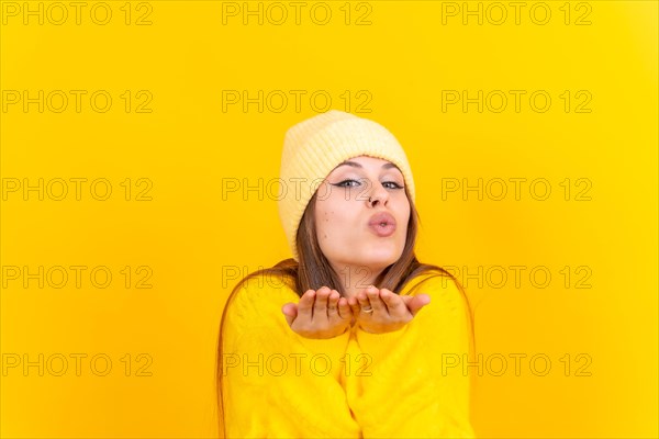 Photo portrait of a young woman blowing a kiss isolated on a yellow background