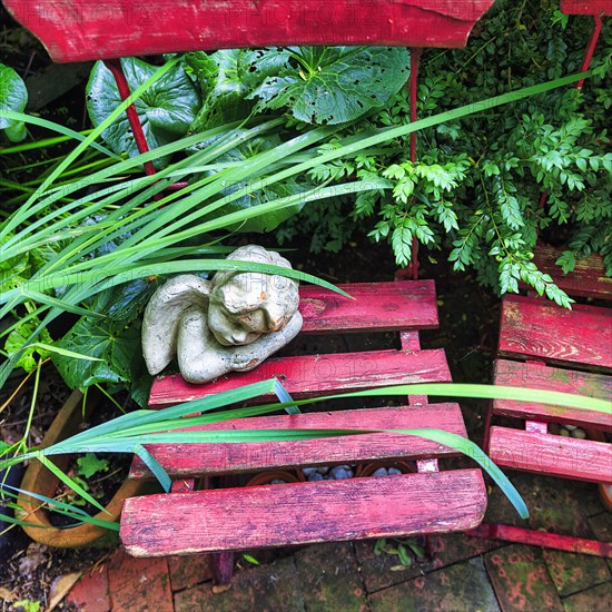 Cherub on an old red garden chair