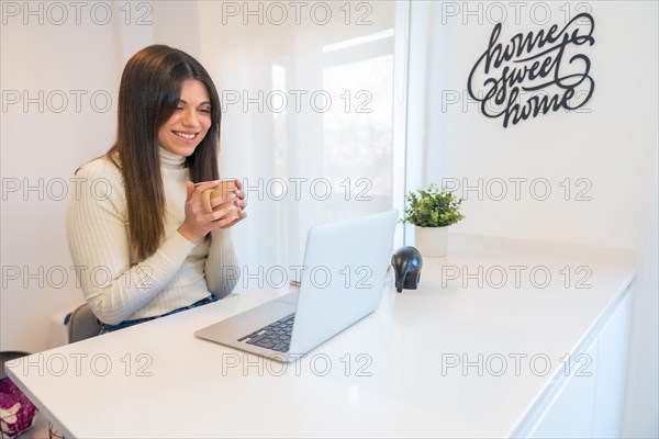 Businesswoman working on a computer with a coffee in her hand