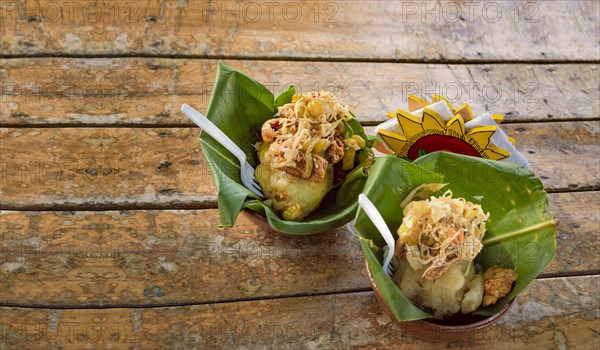 Traditional vigoron in banana leaves served on a wooden table. Two Nicaraguan vigorones served on wood. The vigoron typical food of Granada