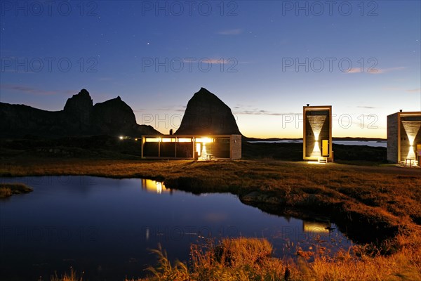 Futuristic wooden houses of a tourist accommodation and the mountain Traenastoppen at dusk