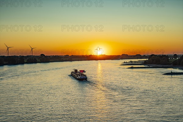 Sunset over the Rhine with inland cargo ship