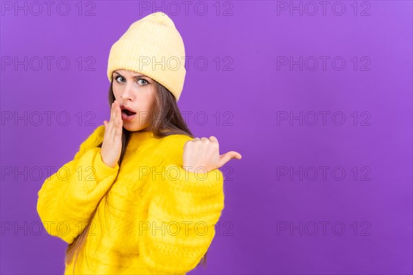 Attractive woman smiling pointing fingers at copy space on purple background