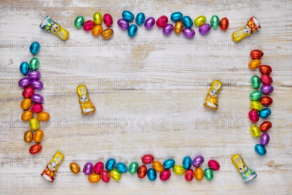 Frame of colourful Easter sweets on wood