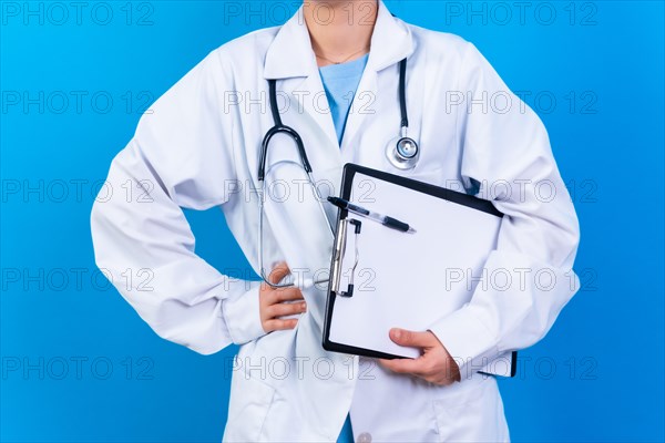 Portrait of smiling female doctor in medical gown standing isolated on blue