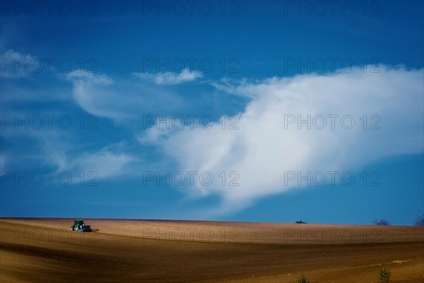 Work with an agricultural tractor in Moravian fields. A wonderful blue sky. Czech Republic