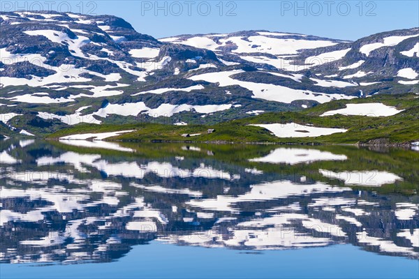 Reflection of partly snow-covered mountains in Lake Stavatn in Haukelifjell