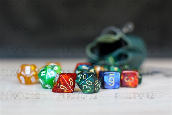 Different colorful role playing dice on table with blurry storage leather bag in background