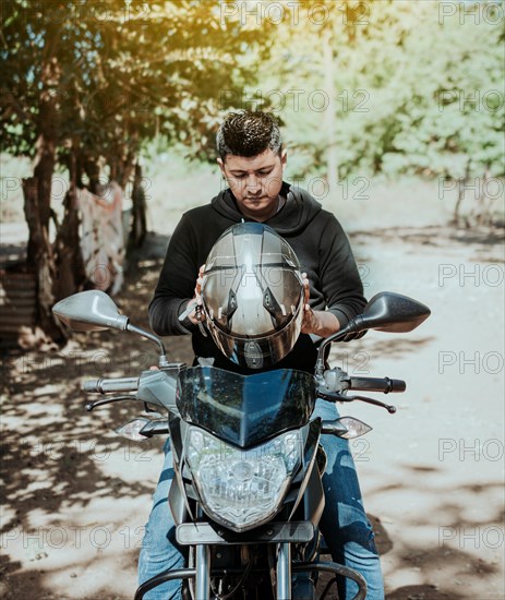 Biker motorcycle safety concept. Young motorcyclist man putting on safety helmet