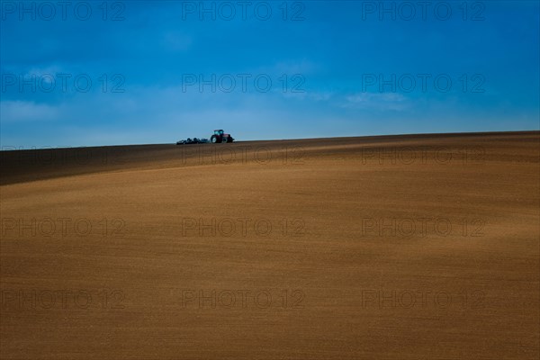 Work with an agricultural tractor in Moravian fields. A wonderful blue sky. Czech republic